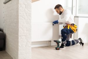 man repairing radiator with wrench. Removing air from the radiator.